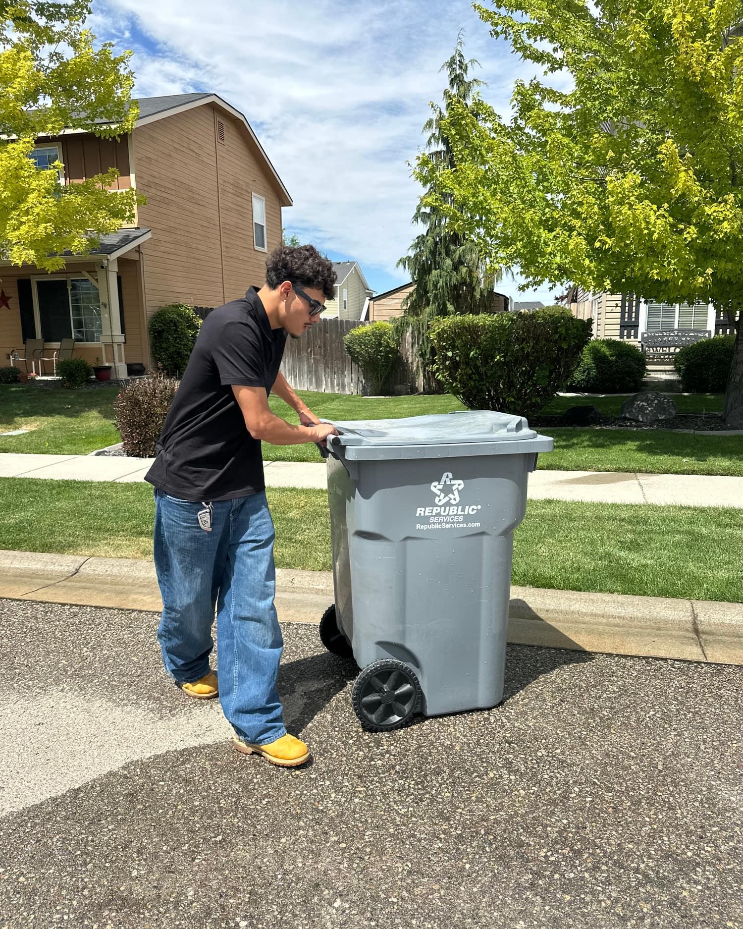 Zeke from Bin Barber tending a freshly cleaned curbside trash bin on a tree-lined Treasure Valley street